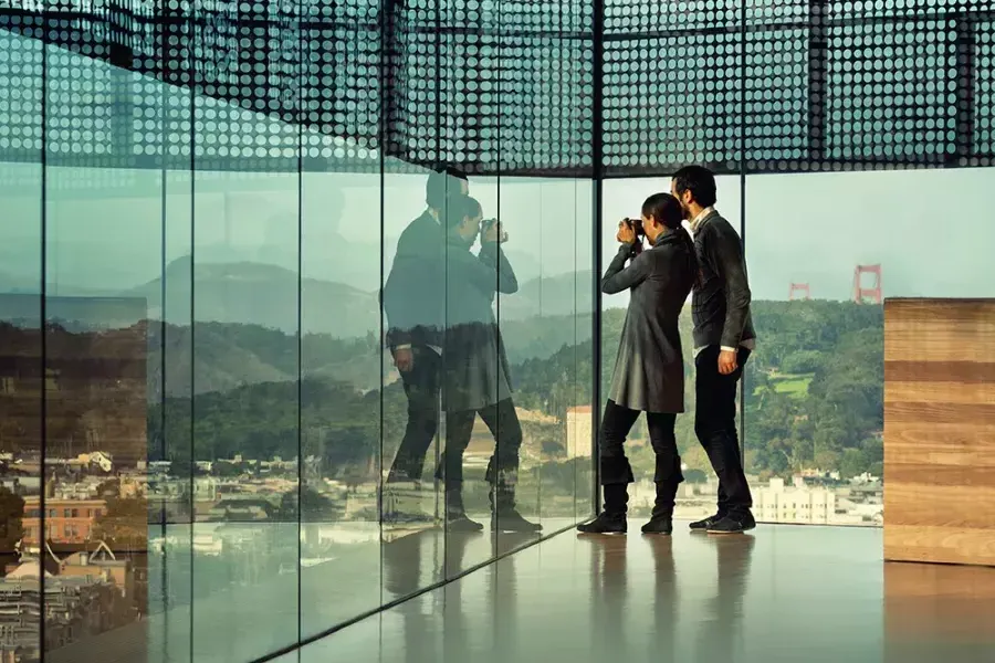 Deux personnes regardent à travers les parois de verre du De Young Museum de 贝博体彩app.